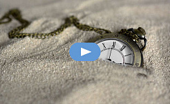 a pocket watch semi-buried in the sand